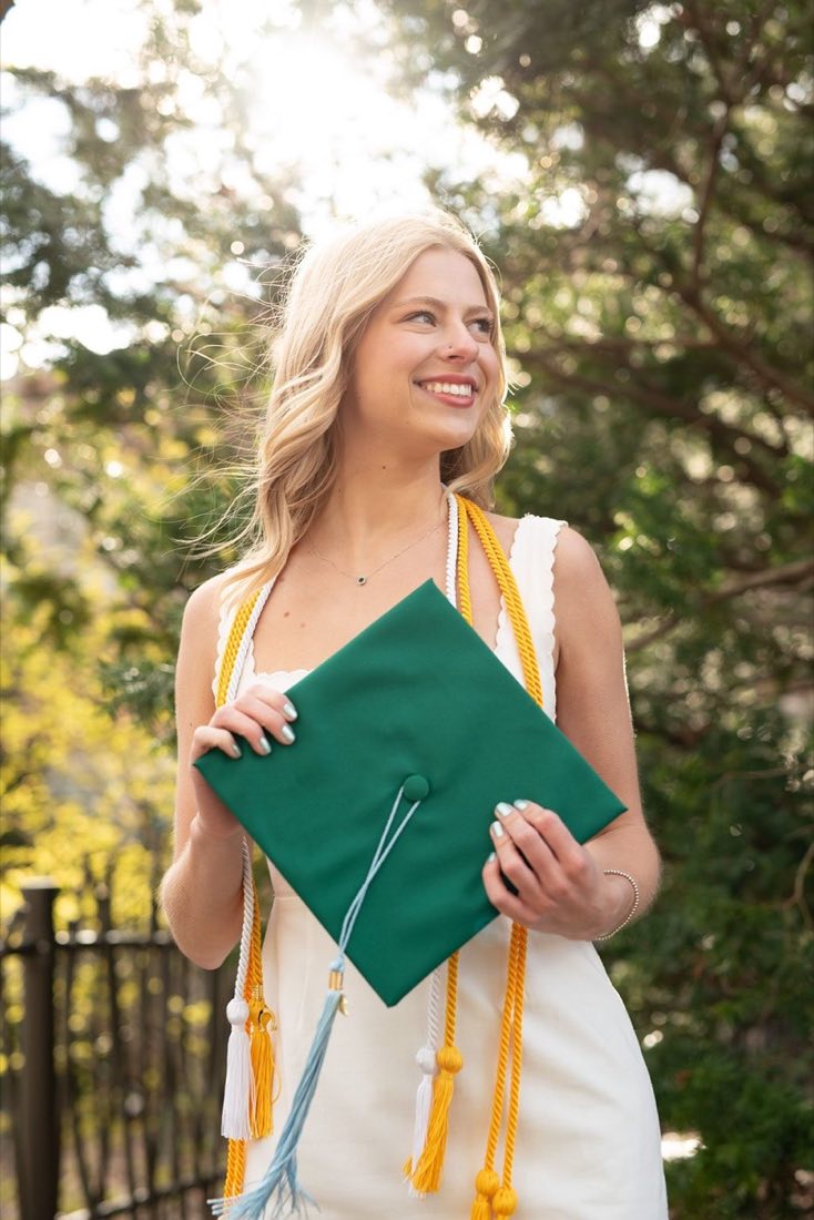 College graduate holding her cap in a green gown