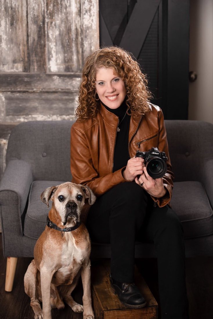 Heidi McClelland seated with her camera and her boxer dog
